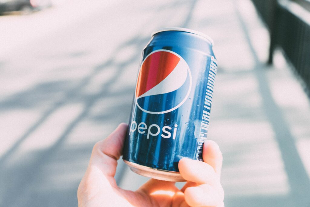 Fotografía lata de Pepsi sujetada por una mano en la calle