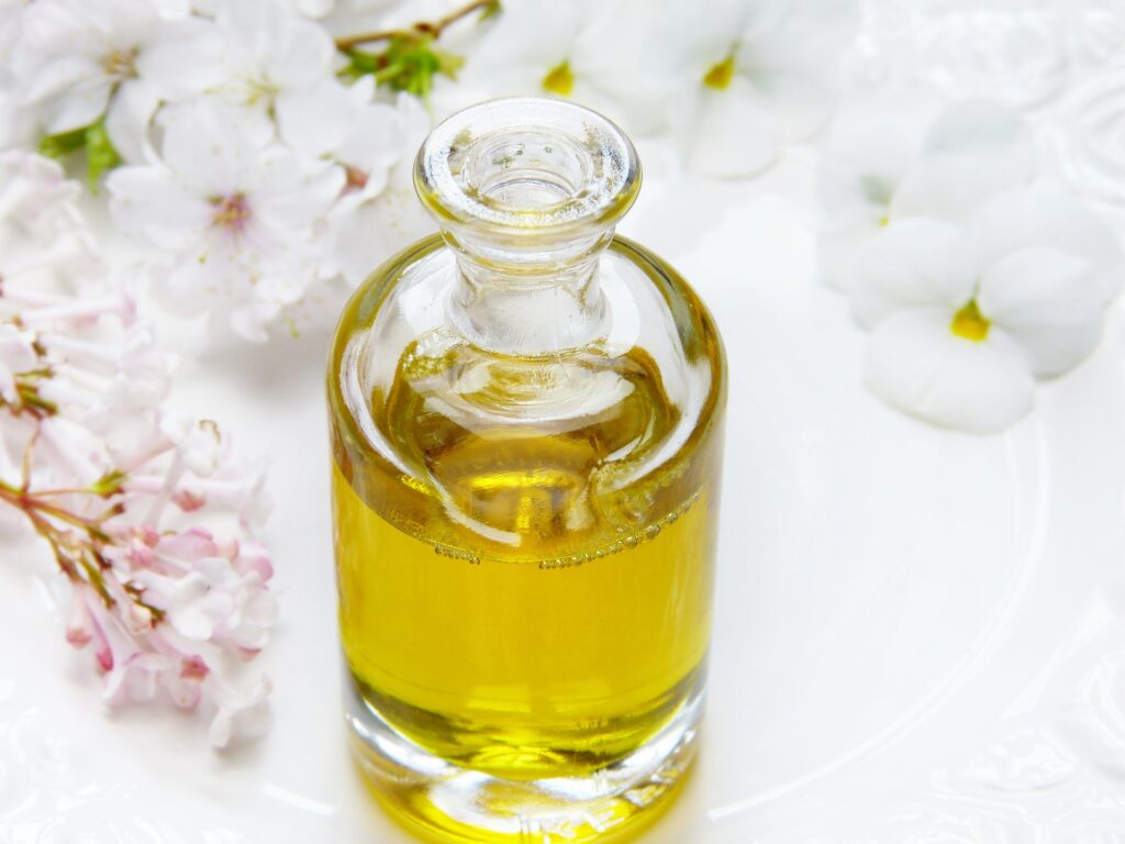 Perfume amarillo en un frasco de cristal sobre una mesa con flores.
