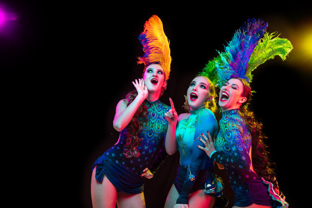 Foto de tres chicas vestidas de carnaval en medio de una función.