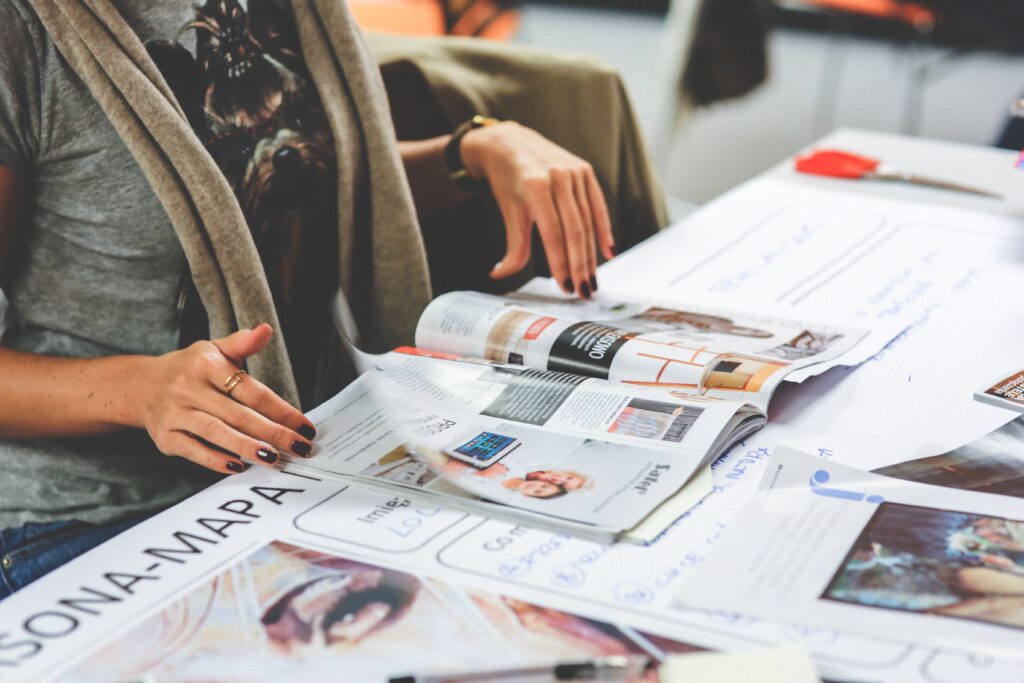 Cómo contactar revista Semana. Foto de mujer viendo revistas en una mesa.